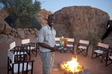 The charming staff serving sundowner cocktails around a campfire at Mowani Mountain Camp, Damaraland, Namibia